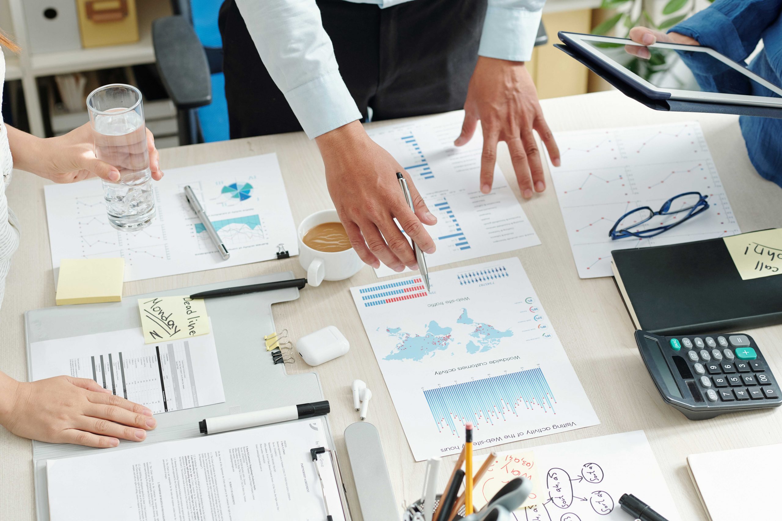 Entrepreneurs standing around a table filled with papers, preparing their digital marketing strategy for the new year