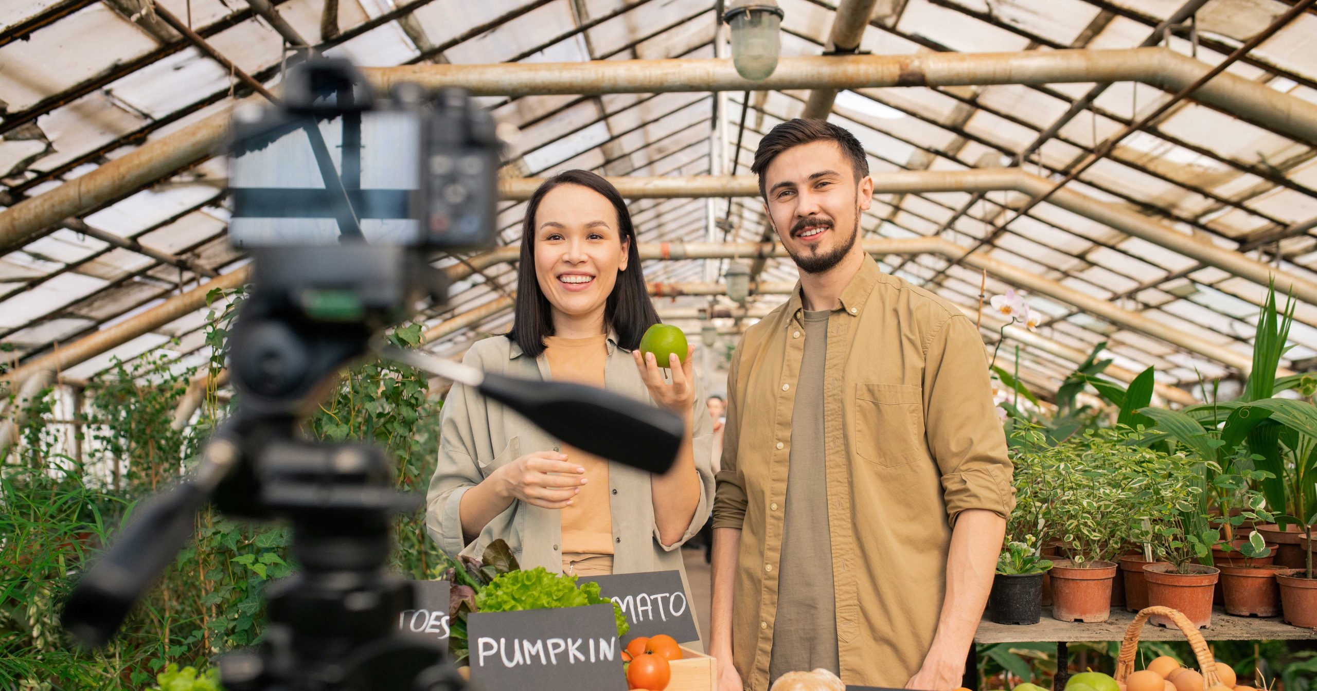 two business owners standing in a green house shooting personalized videos during the holidays for their customers