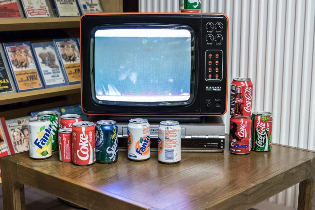 Retro TV, VCR, and soda cans displaying old video marketing