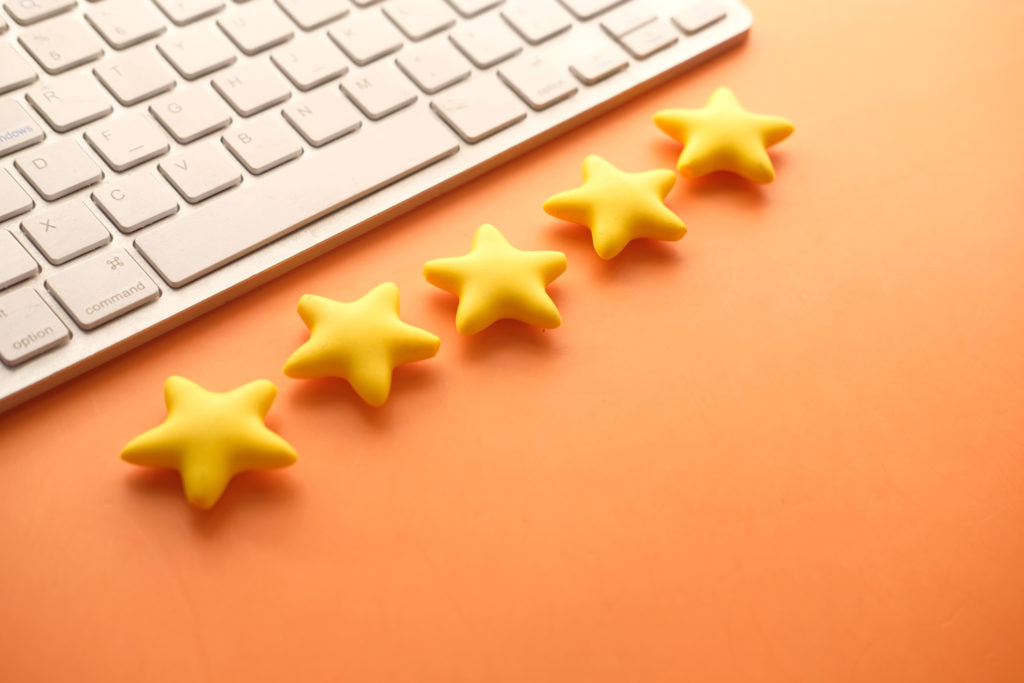 5 gold star next to a keyboard, showing the power of reviews on a small business