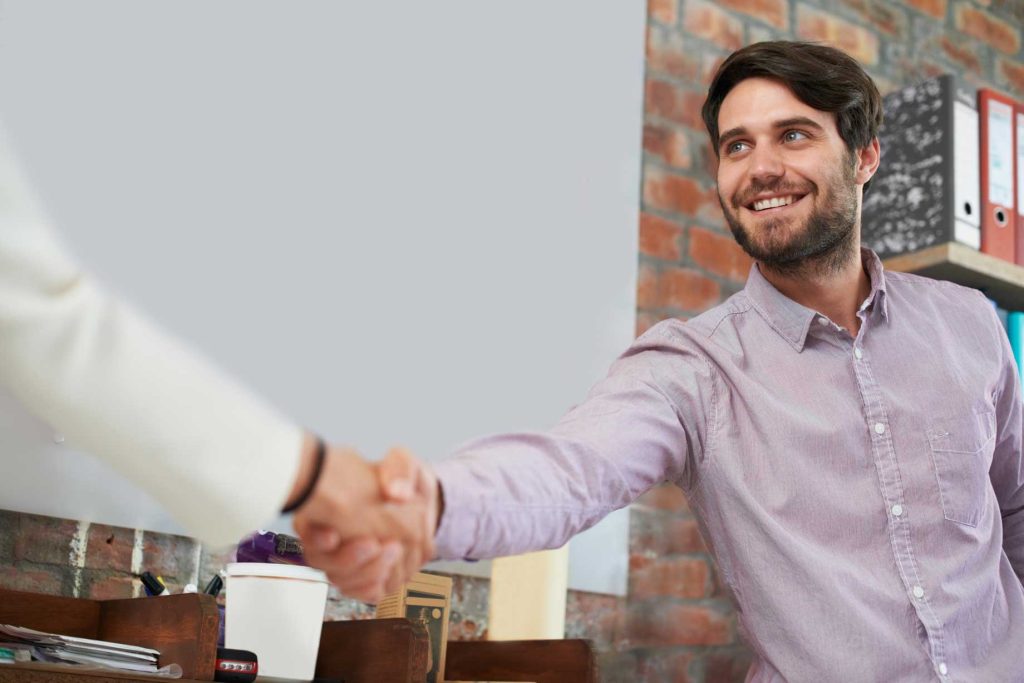 A small business owner shaking hands with a client after making a good first impression of his brand