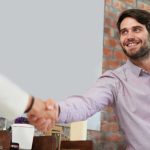 A small business owner shaking hands with a client after making a good first impression of his brand