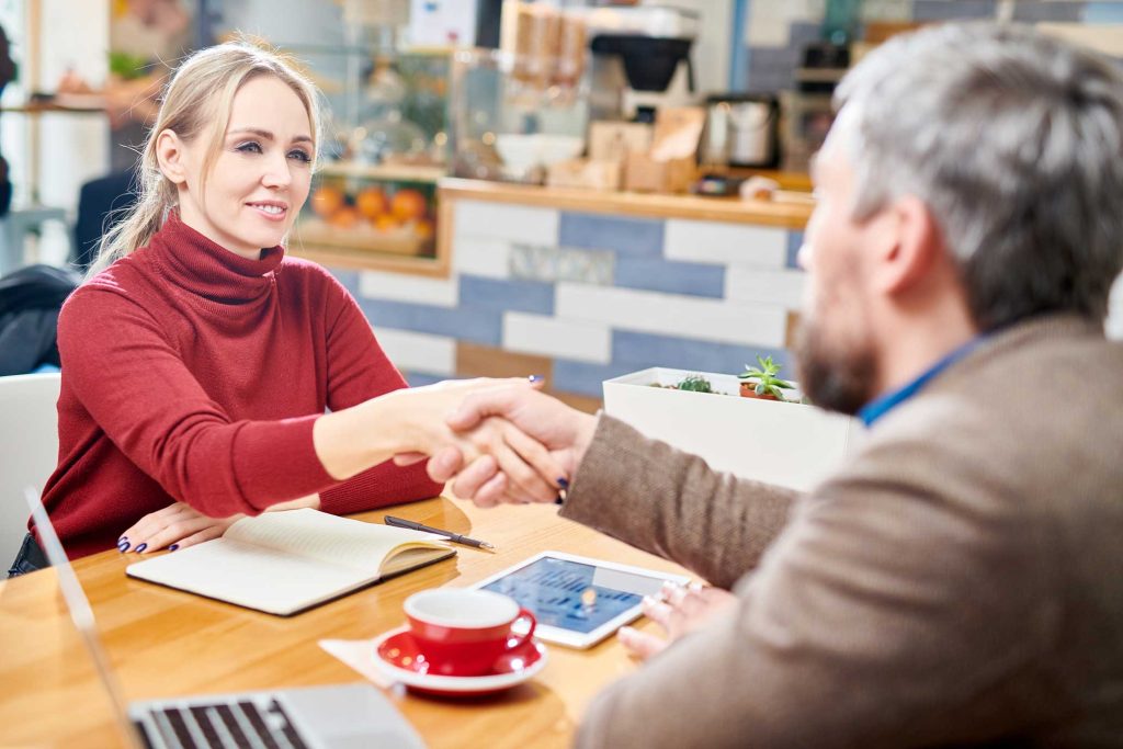 a business owner shaking hands with a customer, demonstrating the power of human-centric marketing